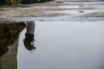 Reflection of man seen in puddle on pier