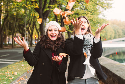 Friends standing against tree