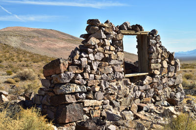 Deteriorating wall with one remaining window frame of stone house in nevada desert ghost town