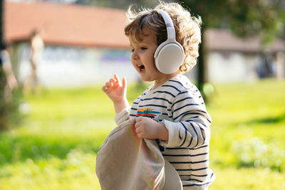 Cute boy wearing headphones walking outdoors