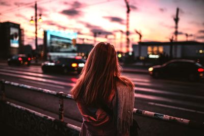 Rear view of woman on car against sky at night