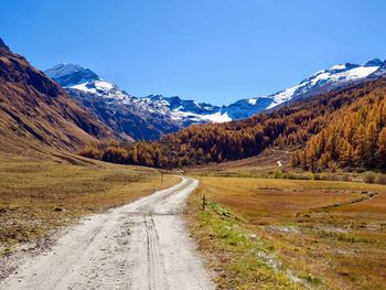 Road amidst mountains against sky during winter