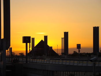 Silhouette bridge and buildings against sky during sunset