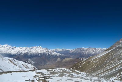 Scenic view of snowcapped mountains against clear blue sky