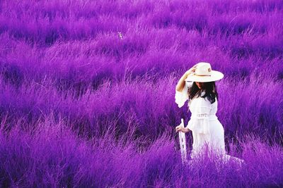 Full length of woman standing by purple flower on field