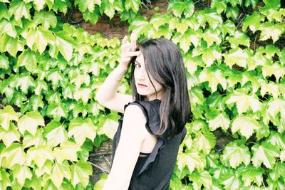 Young woman standing against plants
