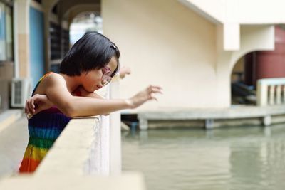 Cute girl looking down while standing by railing