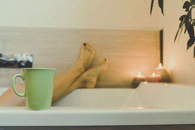 Foot of woman in the water of the bathtub, girl relaxes immersed in bath relaxing candles atmosphere