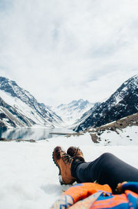 Man lying on snowcapped mountain against sky