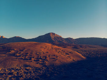 Scenic view of desert against clear blue sky