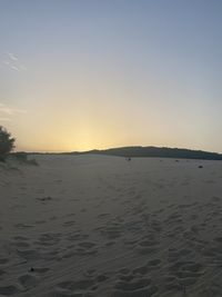 Scenic view of beach against clear sky during sunset