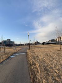 Empty road by city against sky