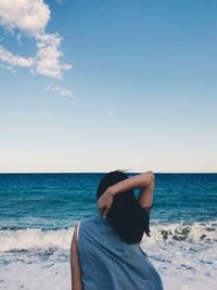 Rear view of woman at beach against sky