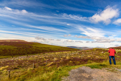 Rear view of man walking on road against sky