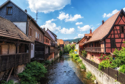 Small german half timbered houses and a river in kaysersberg along the main street. 
