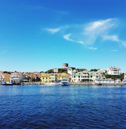 Sea by buildings against blue sky