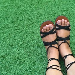 Low section of woman wearing sandals while sitting on field