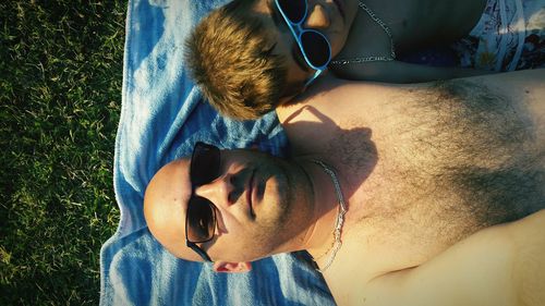 High angle view of father and son wearing sunglasses while lying on blanket