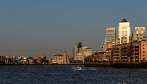 Sea by buildings against clear sky