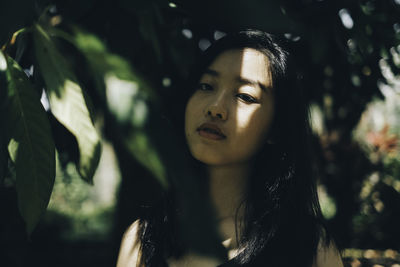 Close-up portrait of young woman against tree