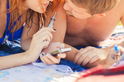 Midsection of smiling woman holding electronic cigarette by man