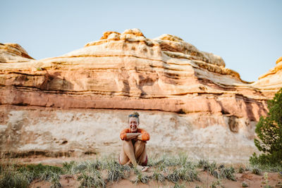 Blonde woman sits crosslegged and laughs in the desert of utah