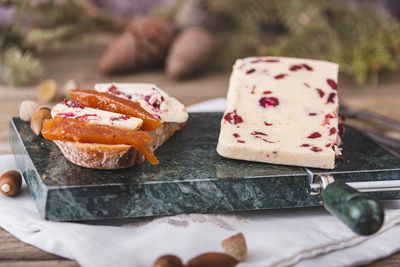 Wensleydale cheese with cranberries, red wine, honey, nuts, raisins on wooden cutting board. 