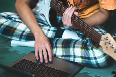 Midsection of man playing guitar