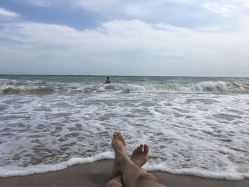 Low section of man on beach against sky