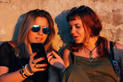 Teenage women together during sunset sharing social media with smartphone