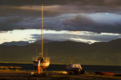 Boats moored on sea by mountains against sky