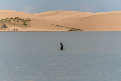 Man surfing in desert against sky