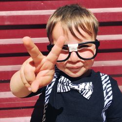 Close-up portrait of cute boy showing peace sign