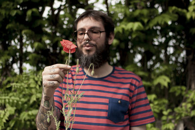 Man holding flower while standing on field