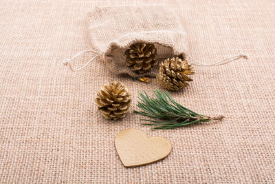High angle view of pine cones with pouch on burlap