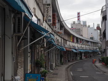 Road amidst buildings in city against sky