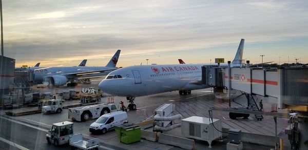 Airplane on airport runway against sky during sunset