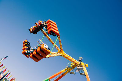 Low angle view of amusement park ride against blue sky