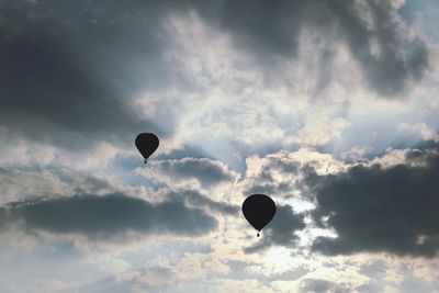 Silhouette hot air balloons against sky