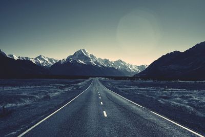 Road leading towards mountains against sky