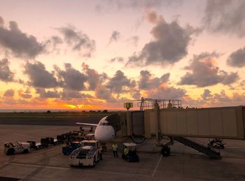 Airplane on airport runway against sky during sunset