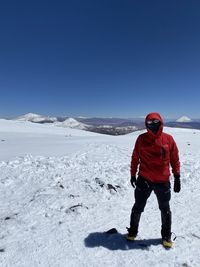 Low section of woman standing on beach against clear blue sky