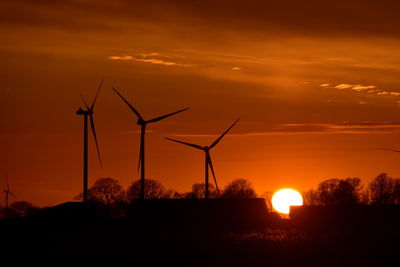 Silhouette windmill on field against romantic sky at sunset