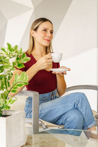 Young woman using mobile phone while sitting on sofa at home