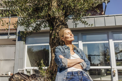 Woman in garden leaning against a tree