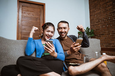 Portrait of smiling friends sitting on sofa at home