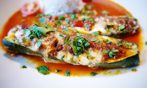 Close-up of stuffed zucchini with rice and gravy in plate