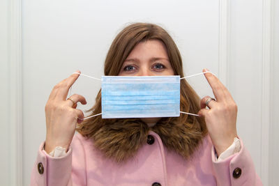 Portrait of woman showing mask against white background