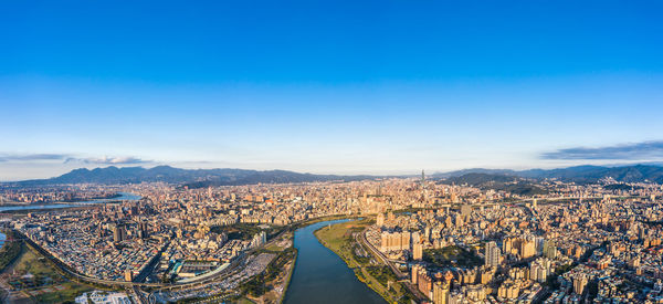 High angle view of city buildings against blue sky