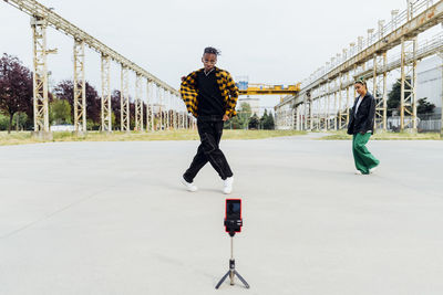 Young man filming dance video through smart phone on footpath